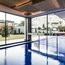 Piscina coperta moderna con grande finestra che dà sul giardino e sulle case